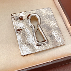 Detailed macro shot of vintage silver square brooch with hammered metal and keyhole detail