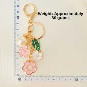 Floral keychain detail with pink flower, green leaf, pearl and 12cm ruler measurement