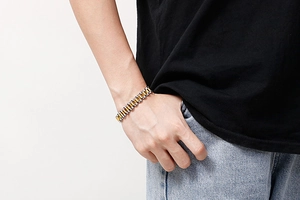 Close-up of a two-tone gold and silver stainless steel watch-style link bracelet on wrist