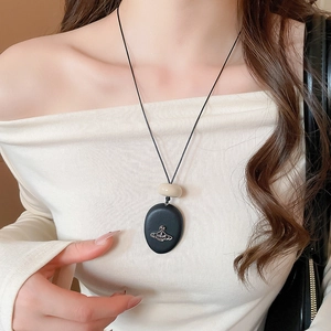 Detail of vintage geometric acrylic Saturn pendant necklace on a minimalist cord