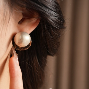 Detailed close-up of large round pearl earring with leopard print back on a model