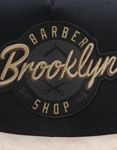 Detailed close-up of BARBER Brooklyn SHOP high-density embroidery on black twill cap