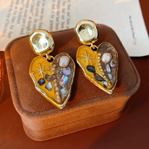 Macro shot of vintage heart drop earrings with enamel and pearl on brown velvet
