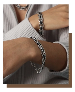 Detail of silver chain bracelet with black leather weave and punk geometric design