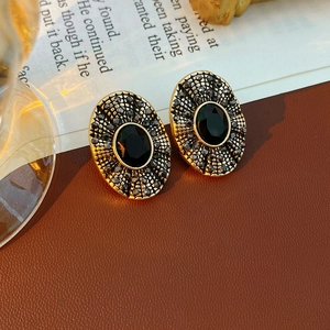 Dettaglio macro di orecchini ovali vintage con pietra nera e pavé di cristalli lucidi