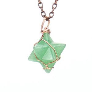 Macro shot of green natural stone Merkaba star pendant with copper wire wrapping