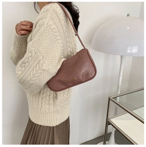 Chic brown leather baguette bag with gold 'BAG' lettering paired with an elegant outfit