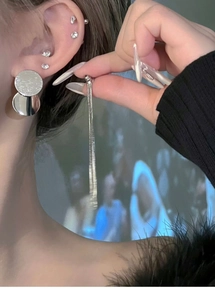 Close-up of silver sequin tassel earrings on model showing geometric design details