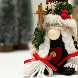 Macro detail of Christmas gnome with red heart button, white braids and wooden ski poles