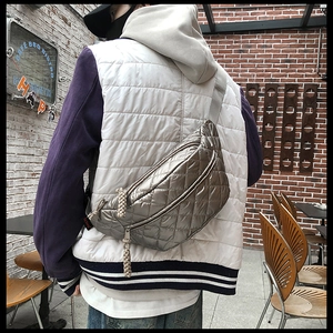 Detailed close-up of a silver quilted puffer waist bag with red logo tag and woven zipper