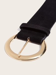 Détail d'une ceinture en cuir noir mat avec une grande boucle ronde en métal doré poli