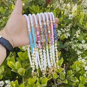 Bohemian colorful clay bead phone charms with pearls held against natural leaves