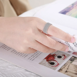 Silver mesh texture ring worn on hand over a magazine background in neutral style