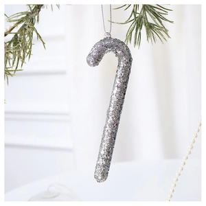 Close-up of a silver glitter candy cane ornament hanging on a green Christmas tree branch
