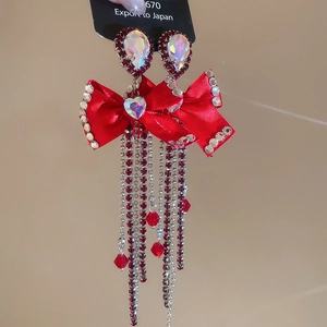 Macro detail of bow earrings featuring red silk, tassels and sparkling rhinestones