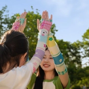 Outdoor shot of two models high-fiving wearing colorful floral print sun protection sleeves