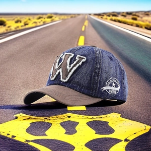 Close-up of vintage denim baseball cap with W embroidery and retro brim on asphalt