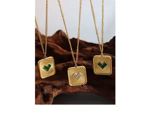 Macro detail of gold vintage square pendants featuring emerald heart-shaped stone settings