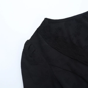 Détail du haut noir à col en V avec bordure en dentelle délicate et tissu jacquard