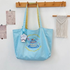 Detail of blue canvas tote bag with cake embroidery and yellow checkered handle