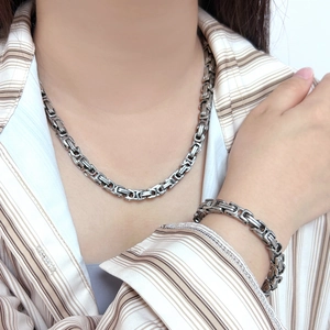 Detail of silver stainless steel Byzantine chain set on model showing woven texture