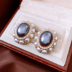 Macro detail of vintage gold oval earrings with gray pearl, small pearls, and pavé crystals