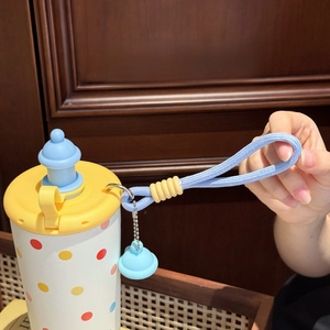 Close-up of the portable woven strap and decorative charm on the cute polka dot water bottle