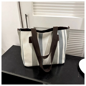 Detailed texture of striped canvas tote bag with durable brown handles on dark wood surface