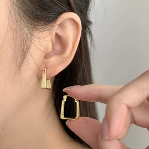 Macro detail of S925 sterling silver stamp on golden geometric U-shaped earrings