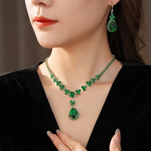 Primo piano di set collana e orecchini a goccia verde smeraldo su velluto nero