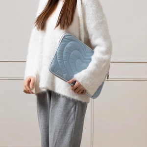 Quilted heart pattern laptop bag in light blue shown held by a model for size perspective
