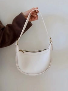 Detail of cream leather hobo bag with gold zipper and adjustable strap close-up