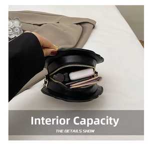 Internal capacity of petal-shaped black crossbody bag showing lipstick and small wallet