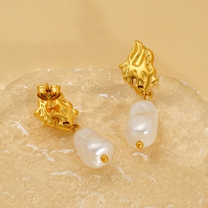 Elegant gold hammered metal earrings with baroque pearls on a textured glass tray