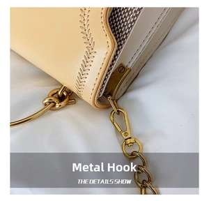 Close-up of beige leather bag featuring decorative leaf stitching and gold chain hardware