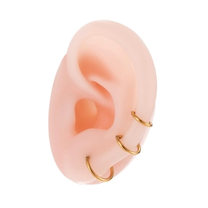 Three golden G23 titanium hinged rings stacked on a model earlobe and cartilage