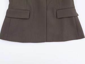 Detailed close-up of dark brown blazer featuring twill fabric and symmetric flap pockets