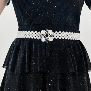 Close-up of pearl waist belt with a floral gemstone buckle on a black dress