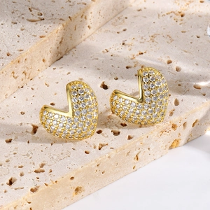 Close-up of 18k gold plated heart earrings with pavé zircon on beige stone base