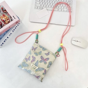 Detailed close-up of a floral butterfly jacquard mini crossbody bag on a desk