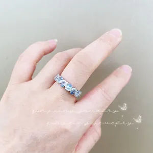Detail of wavy silver ring with blue gemstones and white diamonds on female finger