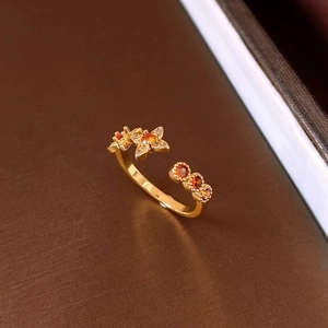 Macro shot of gold plated open ring with orange gemstone flowers and three round stones