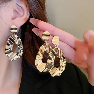 Elegant gold flower tassel earrings with molten metal texture on model for high-end look