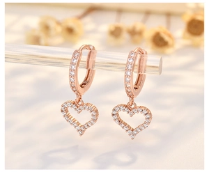 Close-up of rose gold hoop earrings with sparkling zircon heart-shaped pendants