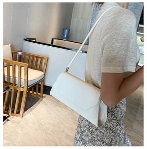 Detailed shot of white crocodile texture faux leather baguette bag with thin strap