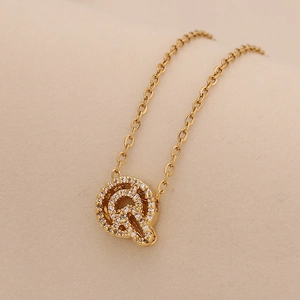 Macro shot of gold letter Q pendant necklace with sparkling cubic zirconia on O-chain