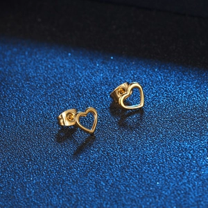 Elegant hollow gold heart stud earrings for women on a dark blue background
