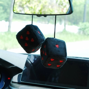 Detail view of plush black car dice with red heart patterns hanging on the rear view mirror
