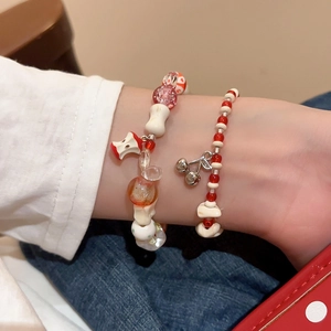 Detail of beaded bracelets featuring apple and cherry charms on a model's wrist