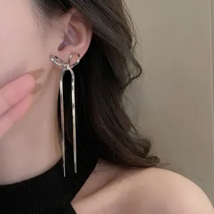 Elegant silver bow earrings with long snake chain tassels on a model for a chic look